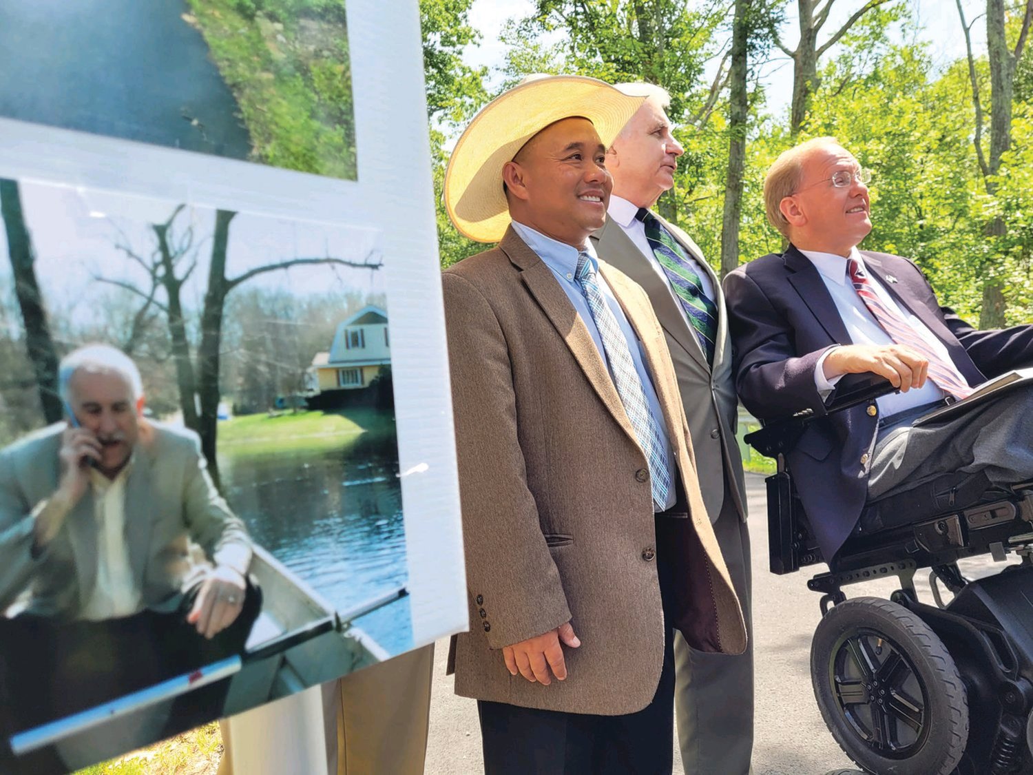 TWO IF BY SEA: In August, Phou Vongkhamdy, U.S. Sen. Jack Reed and U.S. Rep. James Langevin stand near a poster, featuring a photo of Johnston Mayor Joseph M. Polisena in a boat. Members of the Johnston Town Council joined representatives from the United States Department of Agriculture, the Northern Rhode Island Conservation District, U.S. Sen. Jack Reed (D-Rhode Island), U.S. Rep. James Langevin (D-Rhode Island), and state Rep. Deborah Fellela (D-Johnston), at an event near 68 Belfield Drive, Johnston, to celebrate the completion of a floodplain restoration project, aimed at eliminating future flooding.